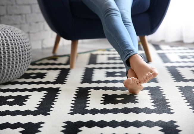 Woman sitting in a chair, resting her feet on an area rug